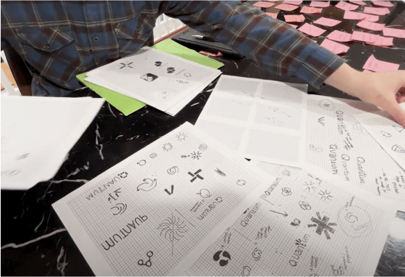 Papers with logo drawings spread across desk