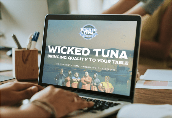 Laptop open with person's hands on keyboard and Wicked Tuna website on screen