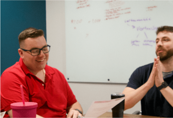 Two smiling co-workers sitting next to each other