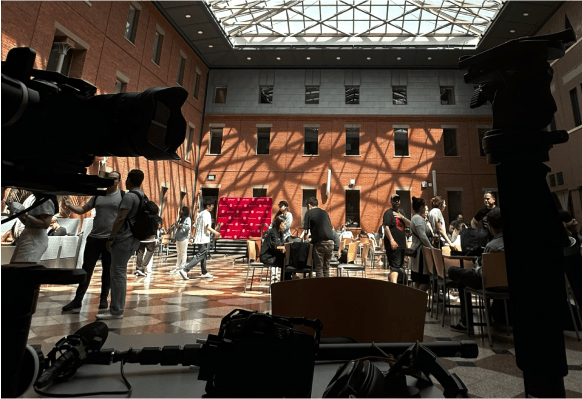 Video crew staging footage inside a dining hall with sunlight shining