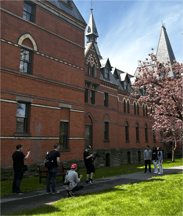 Video crew shooting footage in front large brick building