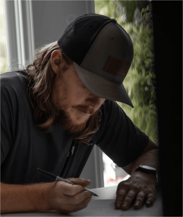 Man with a hat holding a pen over paper