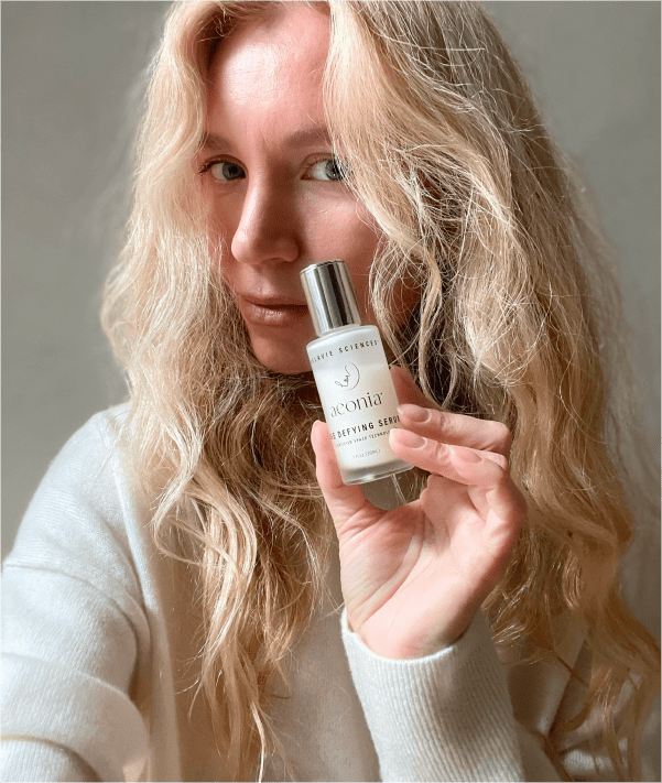 Selfie of a woman holding a skincare bottle